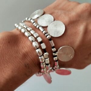Bracciale a tre fili con perle color argento, perle placcate argento e piccoli medaglioni rotondi per un look bohémien. Ideale per chi ama lo stile etnico e desidera un accessorio unico e versatile.