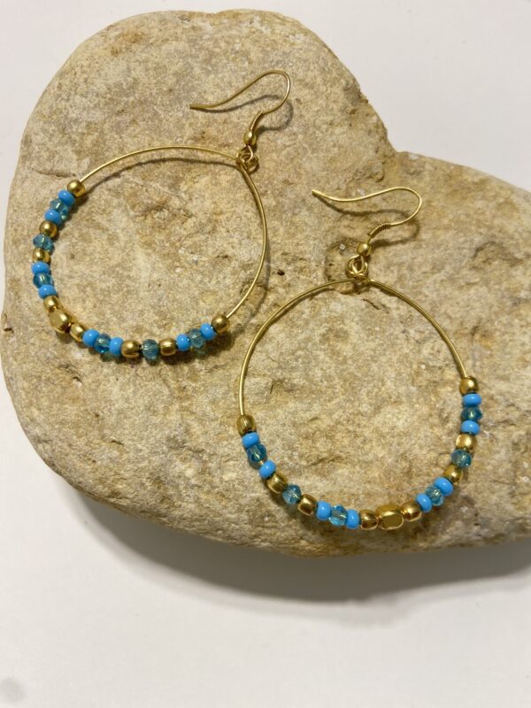Orecchini a cerchio in oro con perline dai colori vivaci. Design leggero e boho-chic, perfetto per ogni occasione. Disponibile in 5 tonalità.